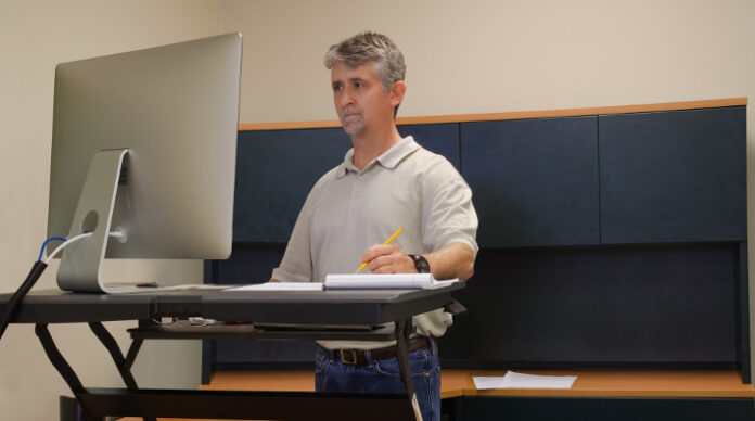 Man using stand up desk in office for good health