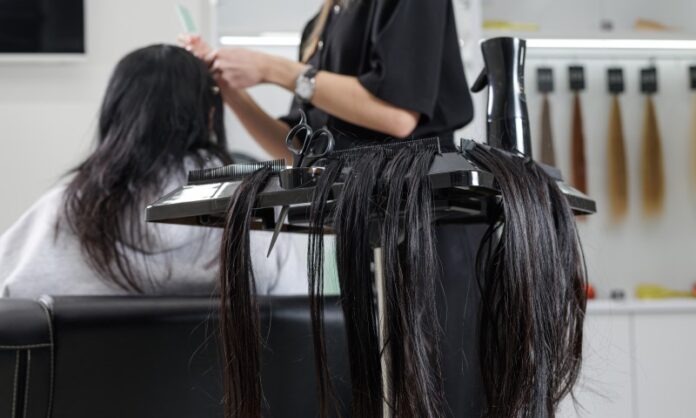 hairstylist putting hair extensions on a customers hair