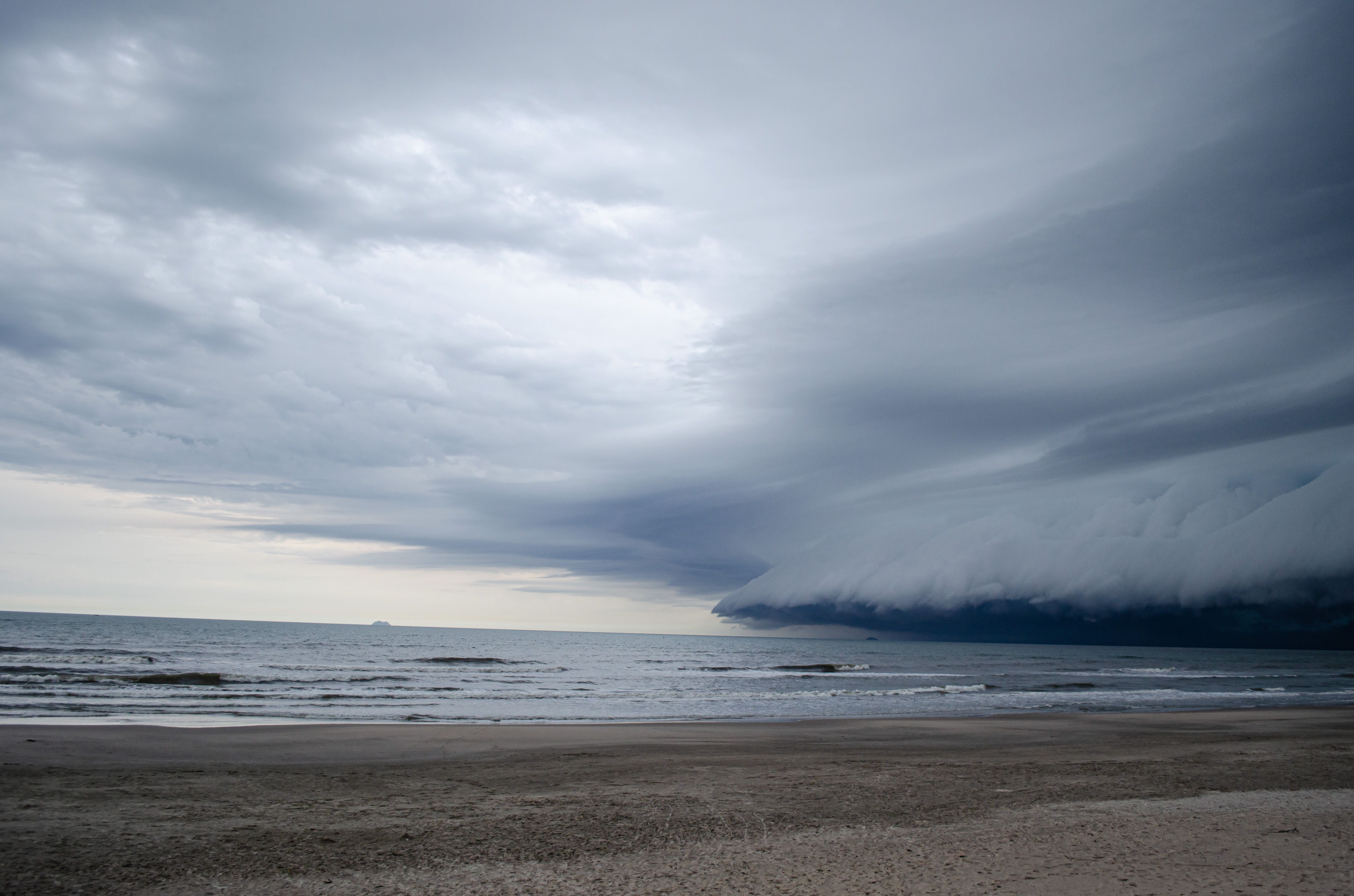 Dark storm clouds gathering over a deserted Pensacola beach during hurricane season