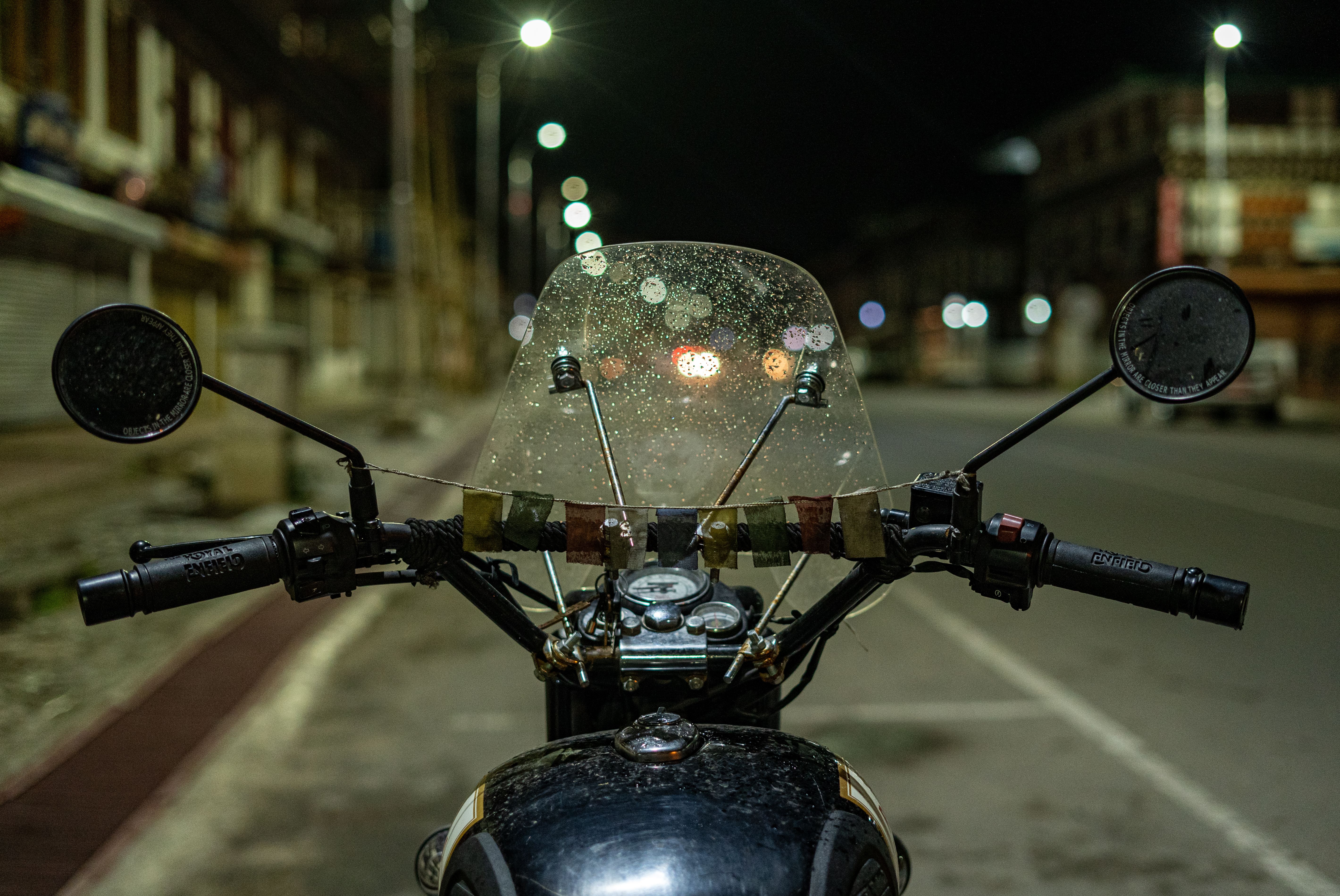 Vintage motorcycle with a rain-speckled windshield on a wet city street at night