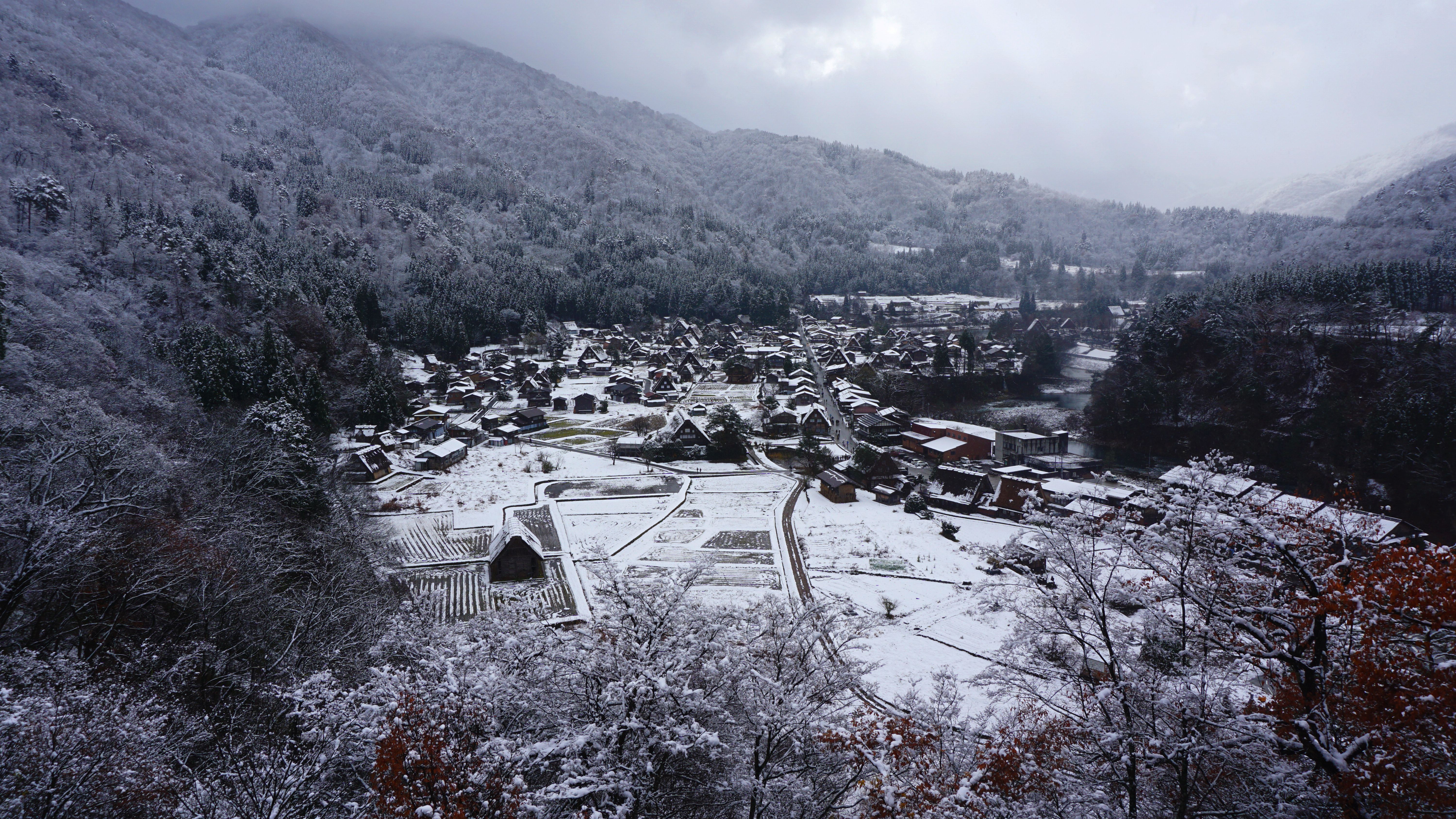 Aerial view of the snow-covered traditional village of Shirakawa in Gifu, Japan, surrounded by mountains in winter