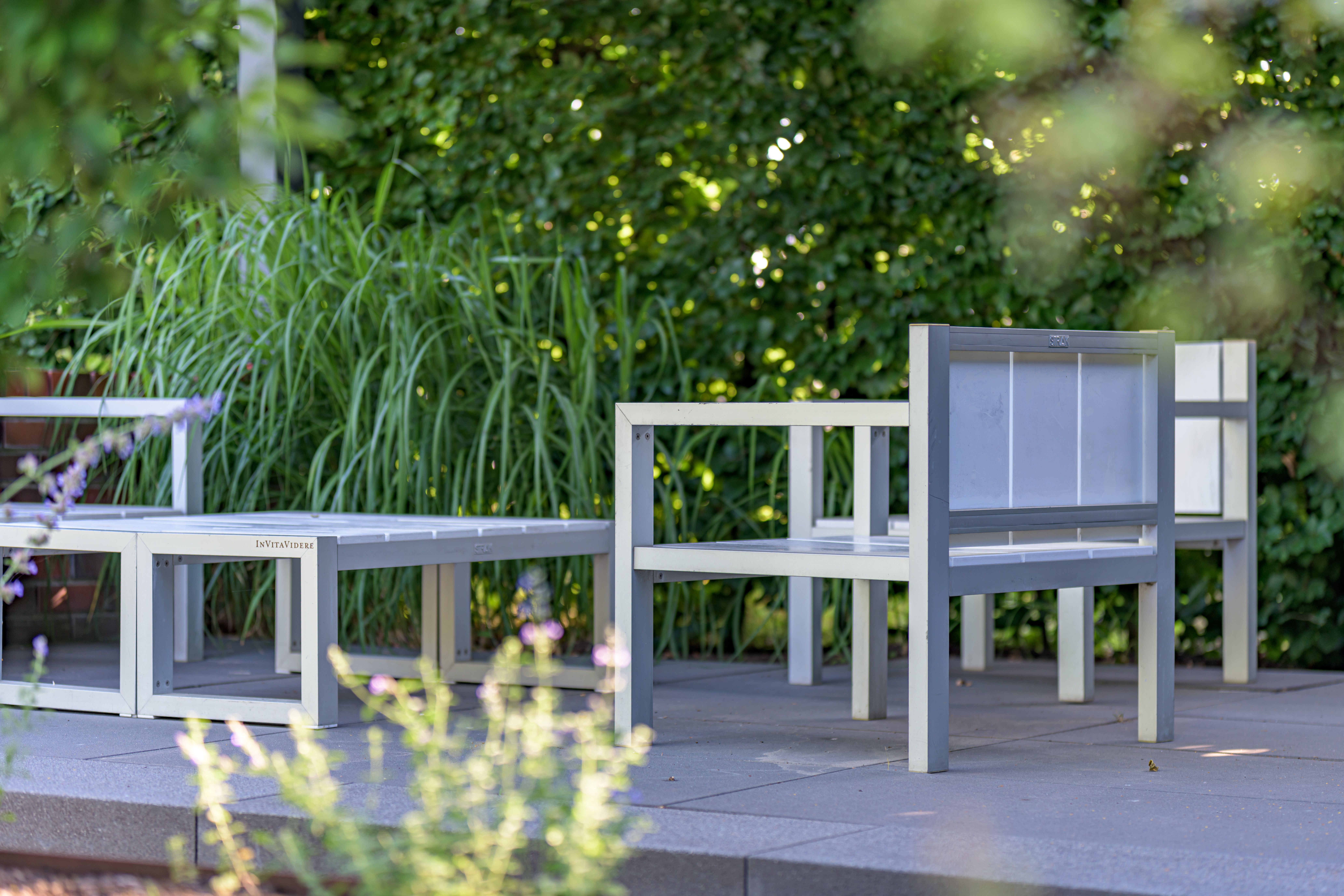 Modern outdoor furniture on a patio surrounded by lush greenery